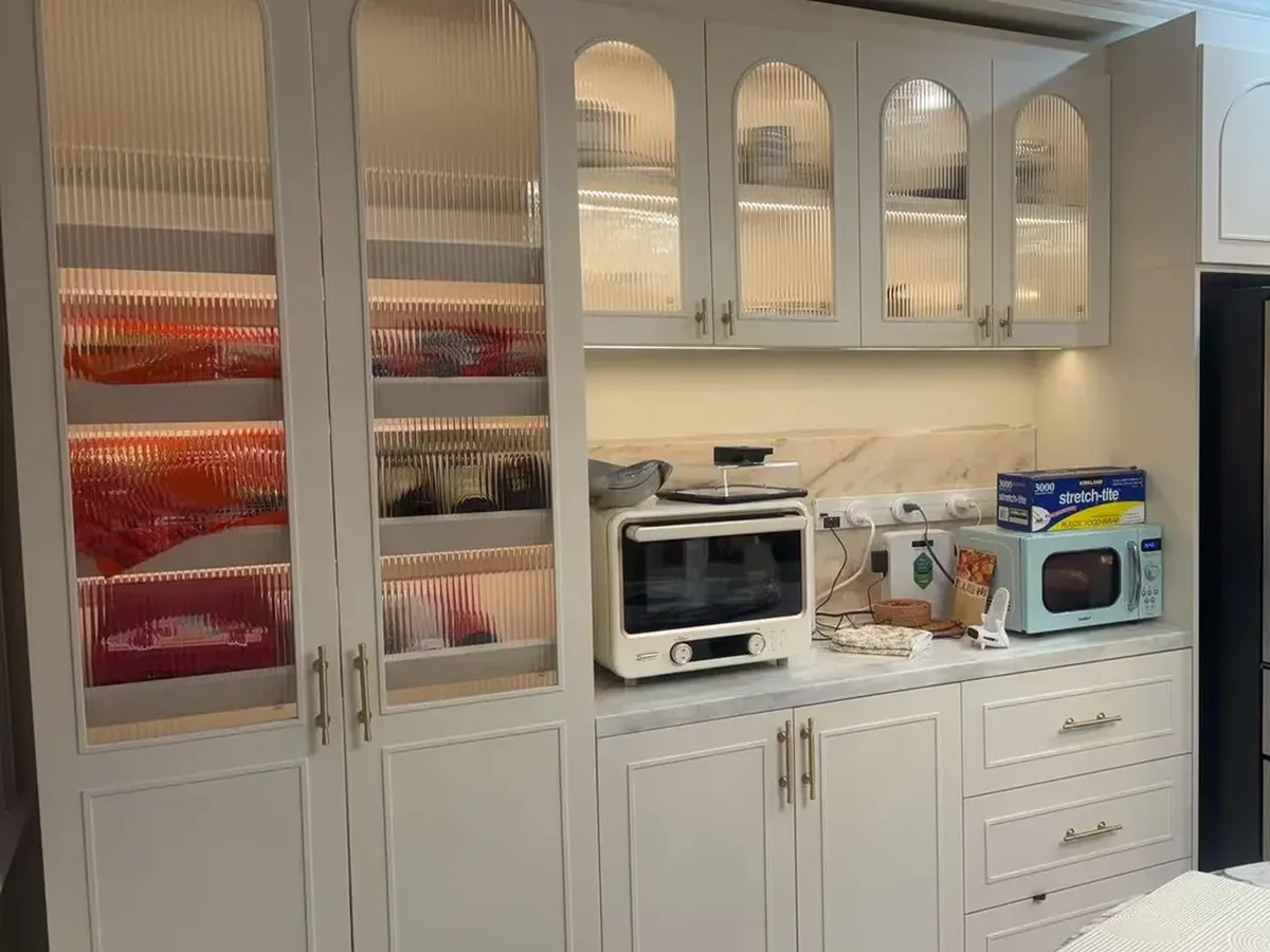 Cream painted kitchen with arched reeded-glass doors in New York