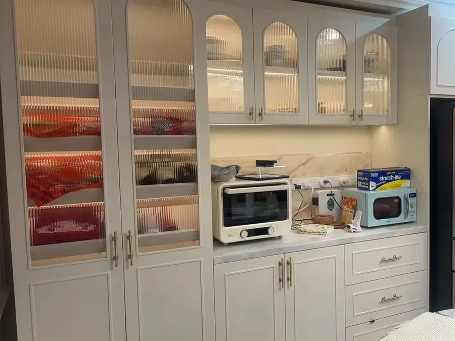 Cream kitchen cabinetry with arched glass-front wall cabinets