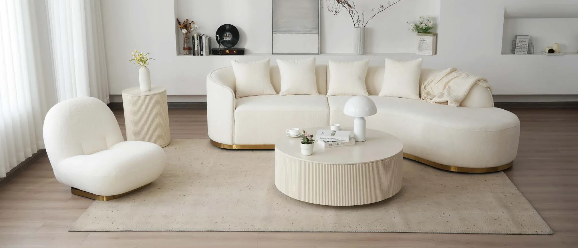 Curved cream bouclé sofa with a matching lounge chair and a round fluted coffee table in a bright living room
