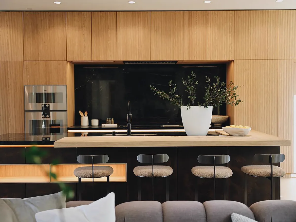 Oak kitchen cabinetry with an island and black stone splashback