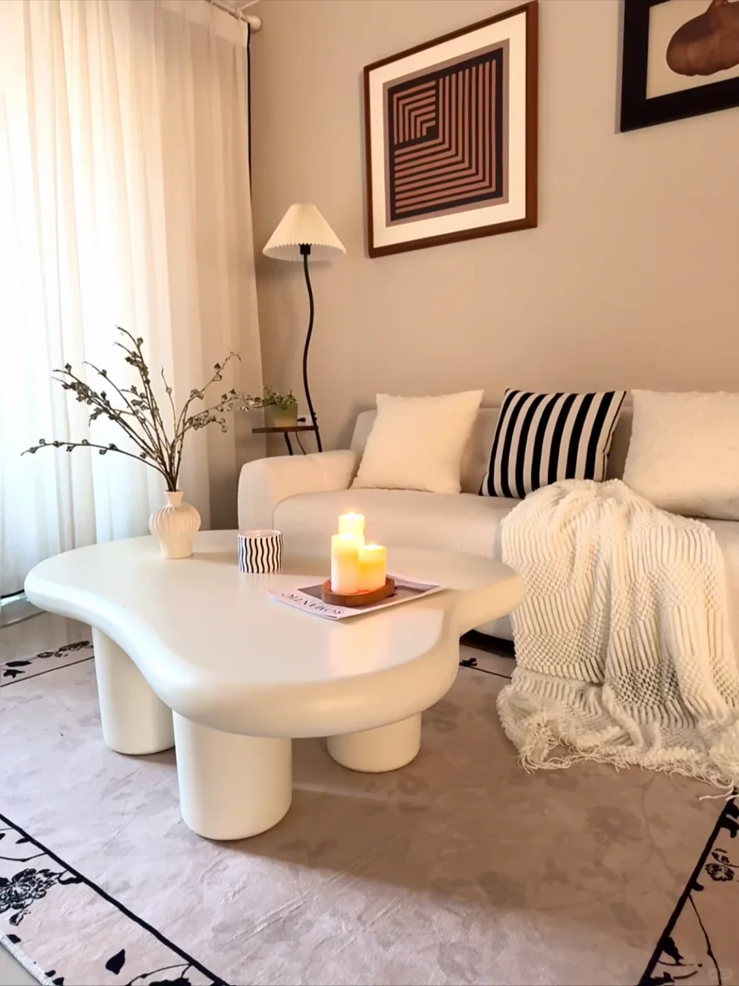 A soft-edged sculptural white coffee table in a compact living room, showing how an organic silhouette improves circulation.