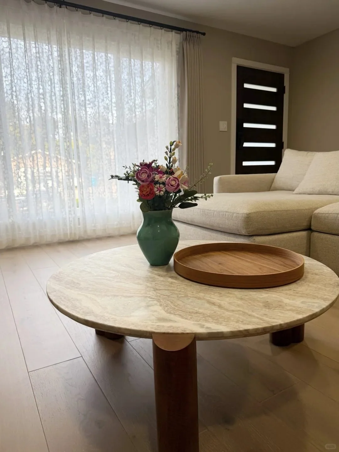 A low round coffee table with a stone top placed in a living room.