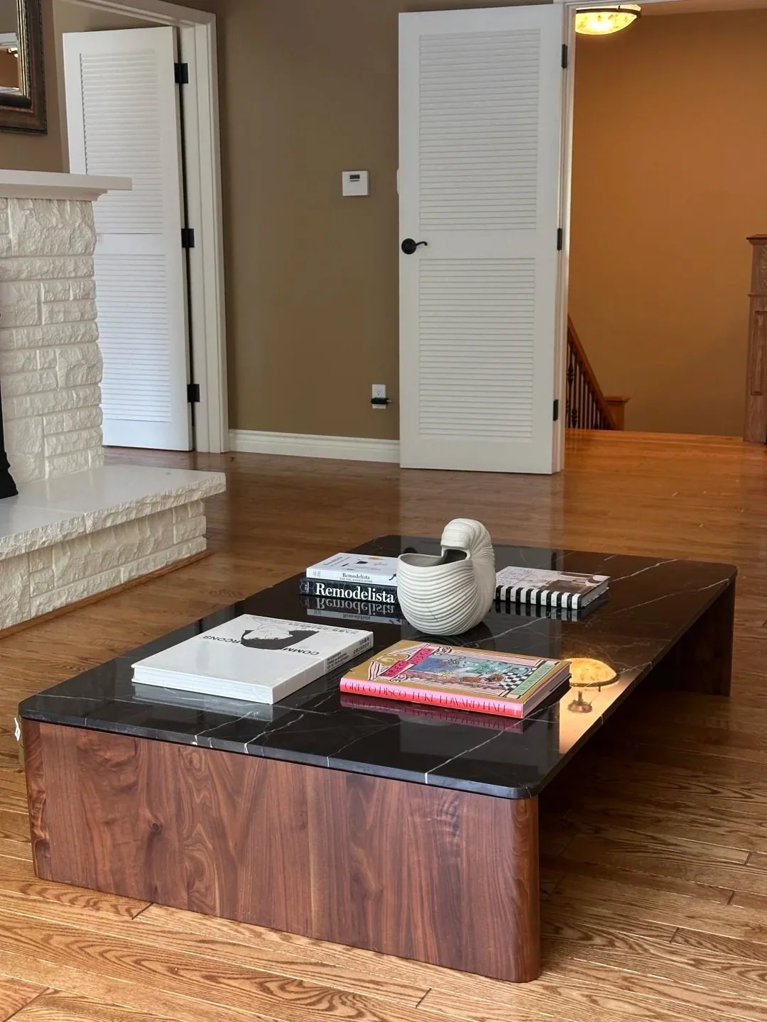 A low rectangular coffee table with a dark stone top and walnut body.