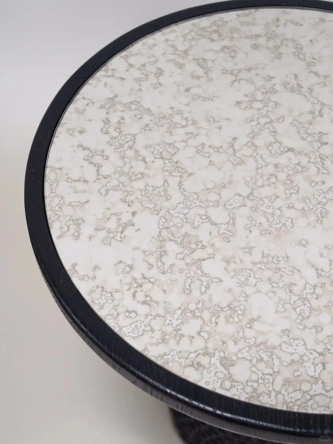 Close-up detail of a stone-look round tabletop with a dark edge frame.