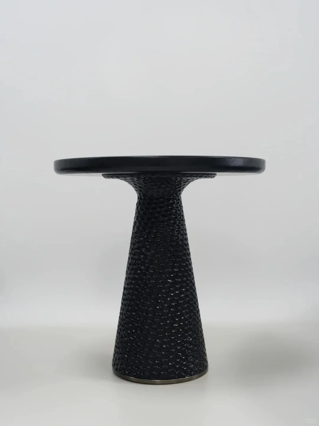 Side view of a textured pedestal side table showing the base profile.