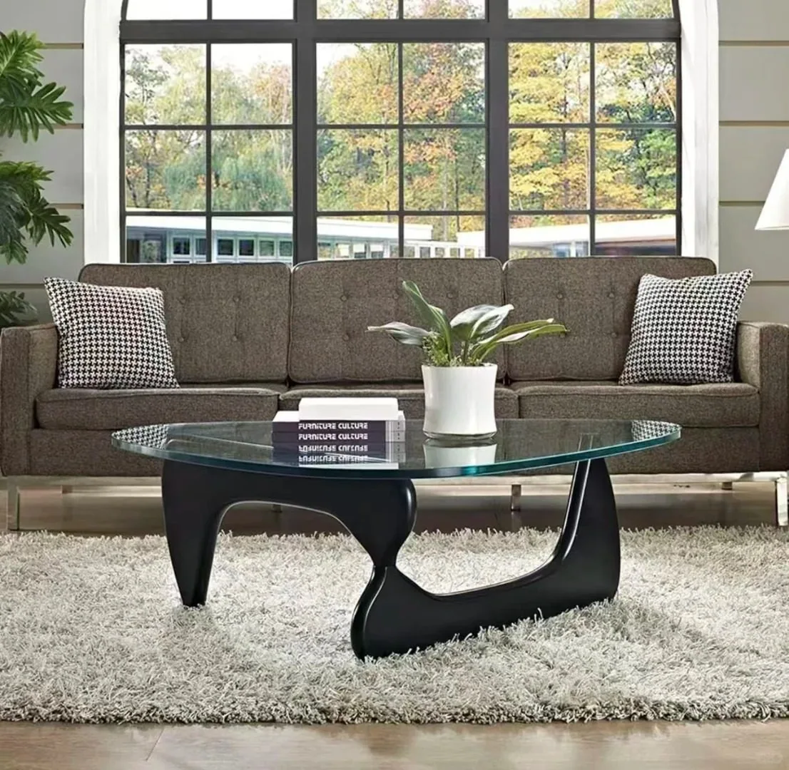 A sculptural black glass coffee table in a living room with a brown sofa.