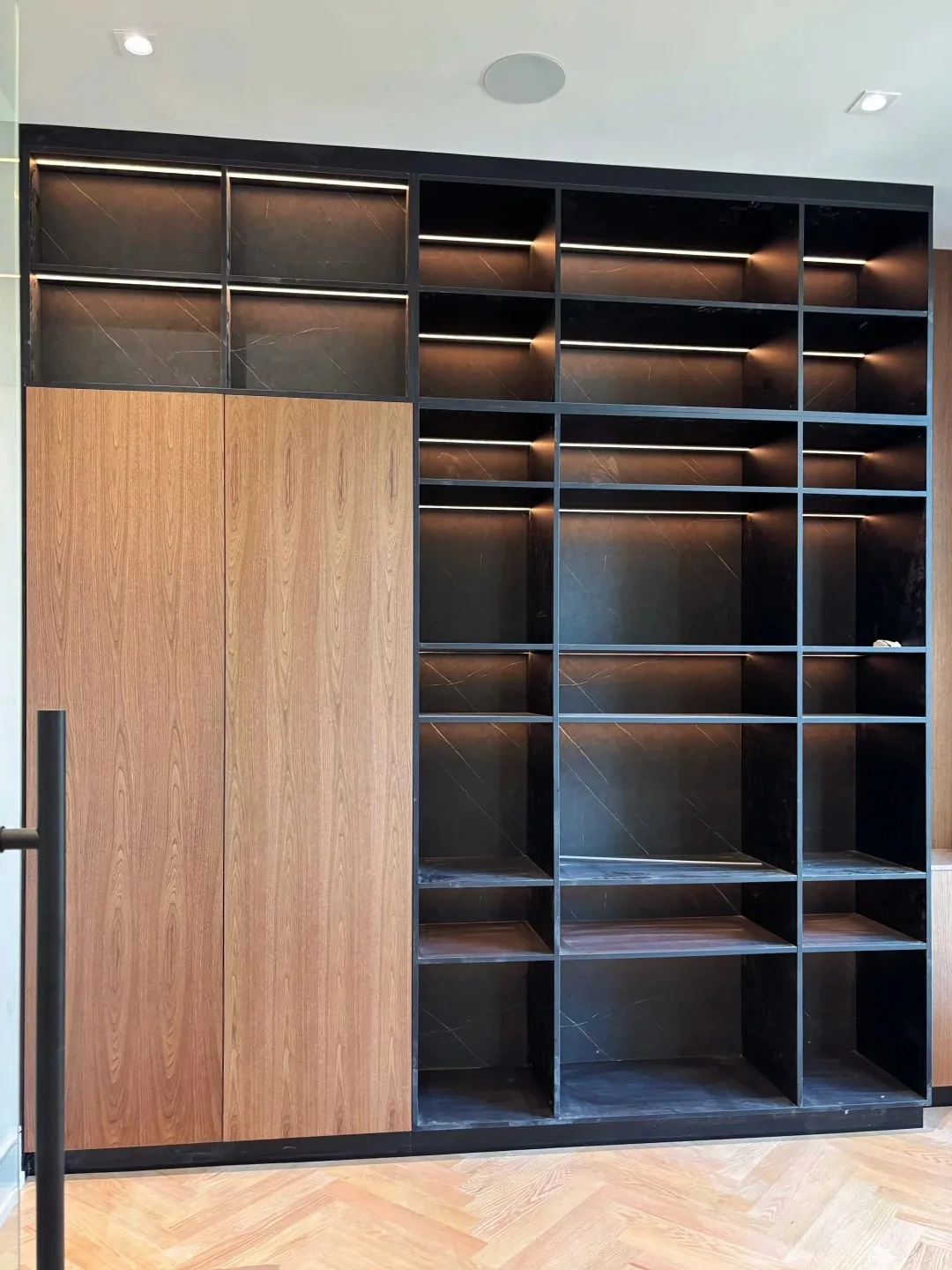 Custom home office built-in shelving with wood doors, dark display niches and integrated lighting