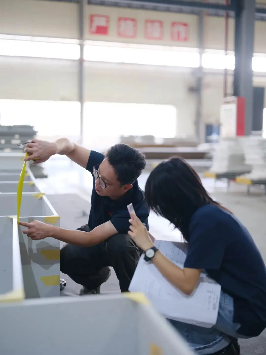 Factory team measuring a cabinet module during custom cabinetry fit and dimension verification