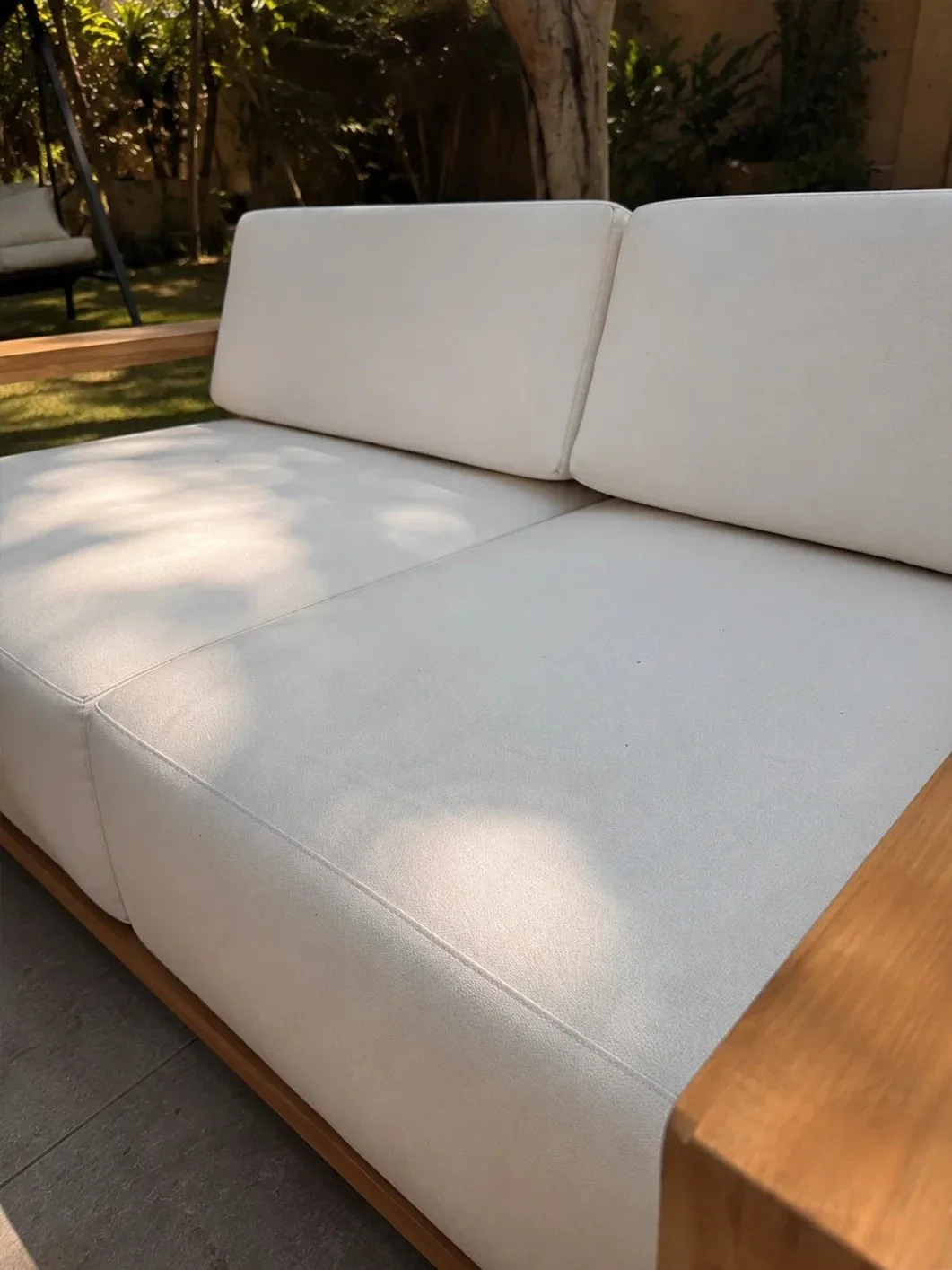 Close-up of an outdoor sofa cushion and solid wood arm detail