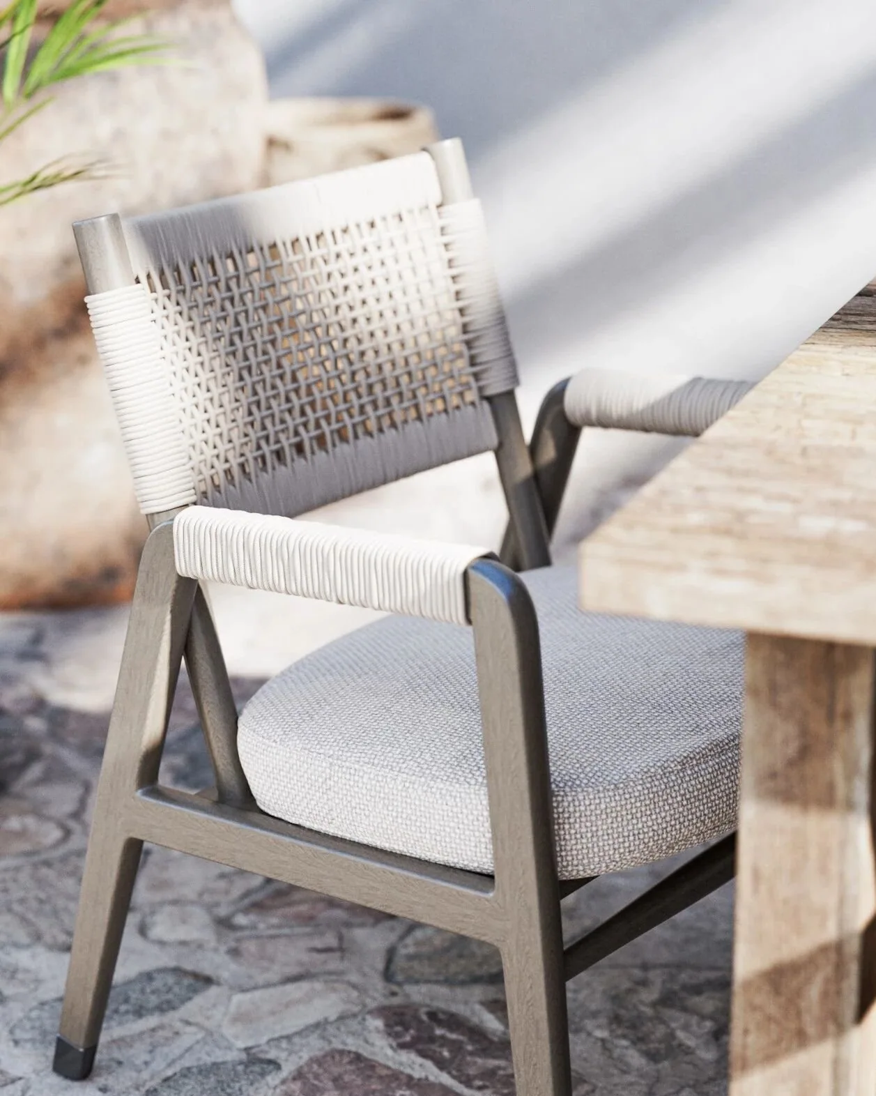 Close-up of a rope-woven outdoor dining chair with cushion and wood-look frame