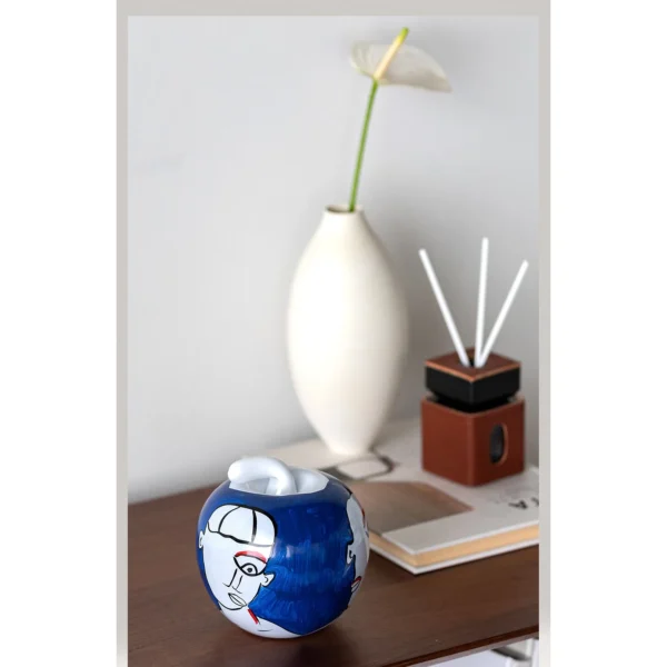 Hand-Painted Abstract Face Blue Glass Apple Ornament in blue — in a room setting