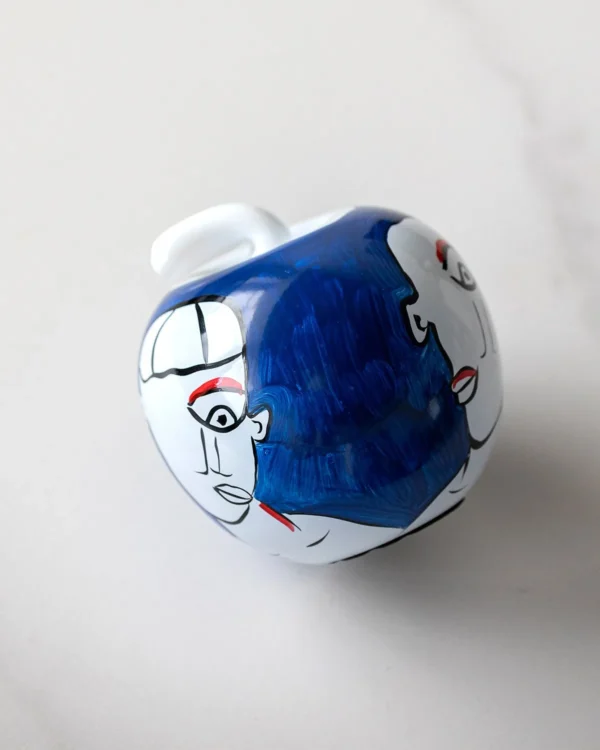 Hand-Painted Abstract Face Blue Glass Apple Ornament in blue — in a room setting