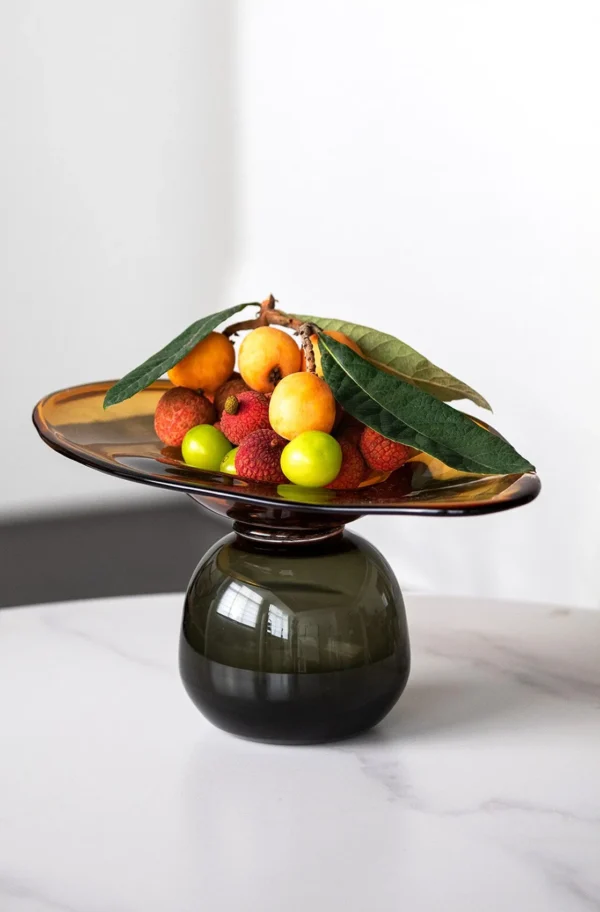 Amber and Black Hand-Made Footed Glass Fruit Bowl in clay — in a room setting