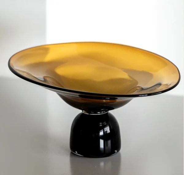 Amber and Black Hand-Made Footed Glass Fruit Bowl in clay — in a room setting