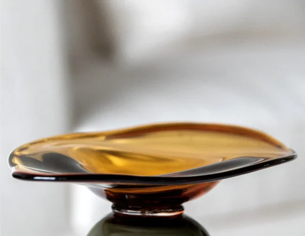 Amber and Black Hand-Made Footed Glass Fruit Bowl in clay — in a room setting
