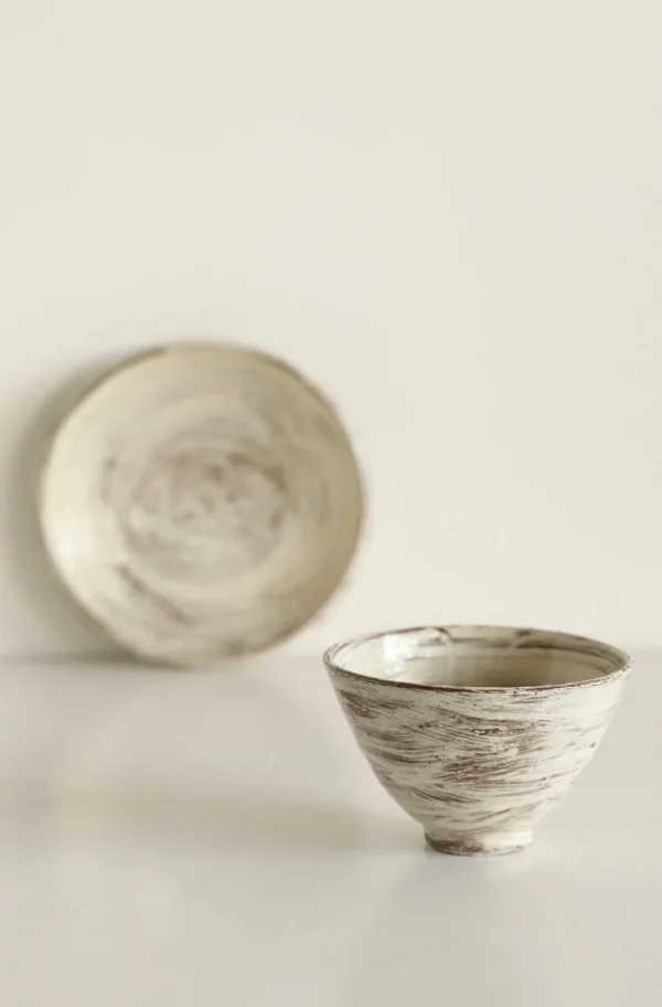 Artist Collaboration Brushed Ceramic Conical Bowl and Plate in ivory — in a room setting