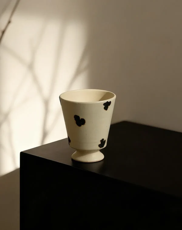 Artist Collaboration Dotted Stoneware Latte Cup, Cream in oatmeal — in a room setting
