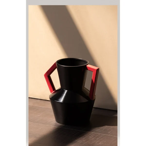 Angular Black Ceramic Vase with Red Square Handles in black — in a room setting