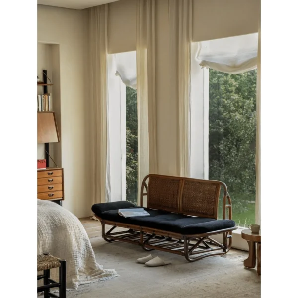 Rattan Daybed with Upturned Ends and Black Corduroy Cushion in natural oak — in a room setting