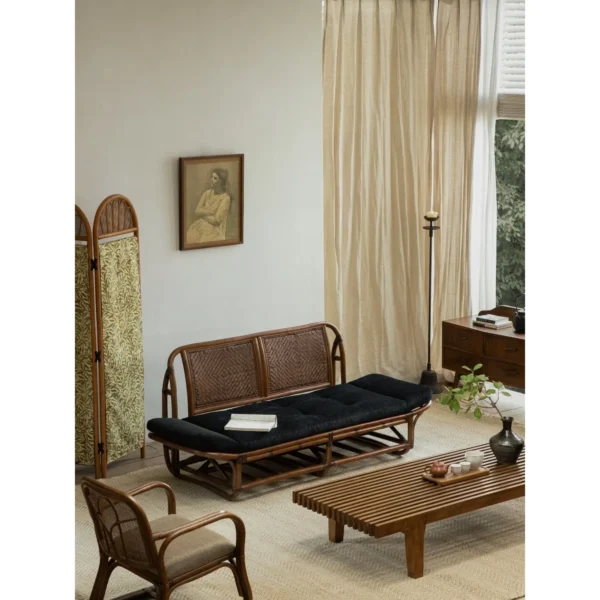 Rattan Daybed with Upturned Ends and Black Corduroy Cushion in natural oak — in a room setting