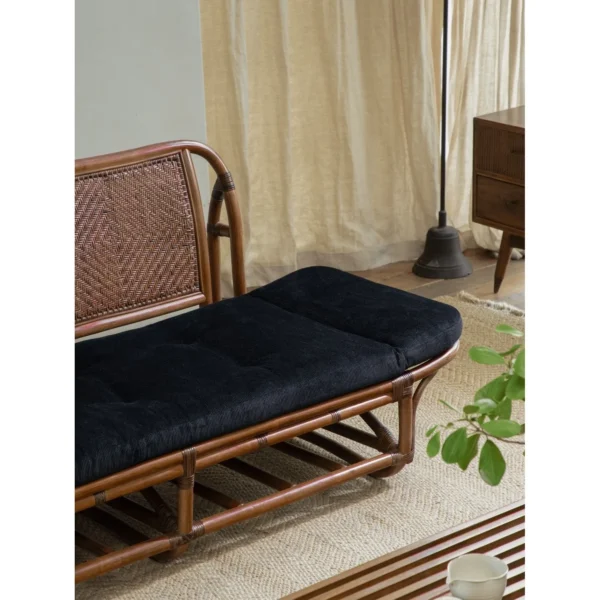 Rattan Daybed with Upturned Ends and Black Corduroy Cushion in natural oak — in a room setting