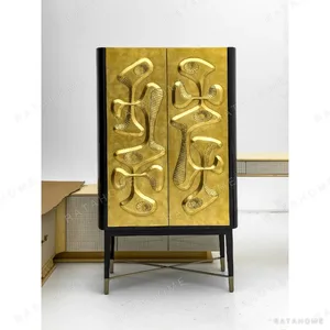 Gilded Relief Decorative Tall Cabinet on Brass Legs in brushed brass — in a room setting