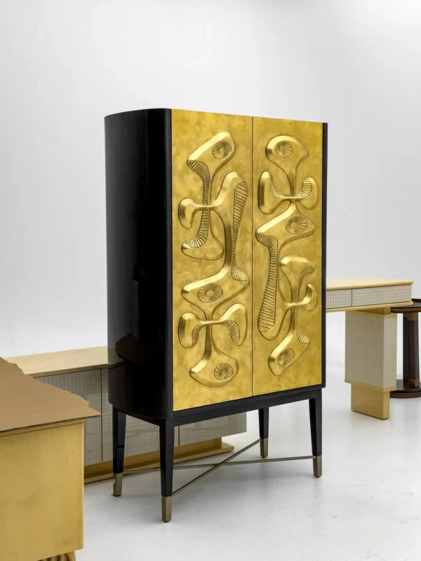 Gilded Relief Decorative Tall Cabinet on Brass Legs in brushed brass — in a room setting
