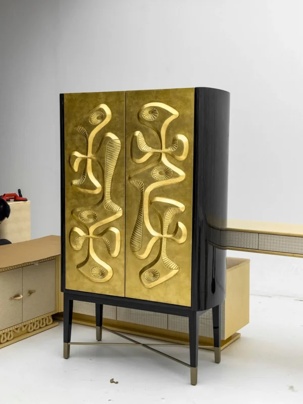 Gilded Relief Decorative Tall Cabinet on Brass Legs in brushed brass — in a room setting
