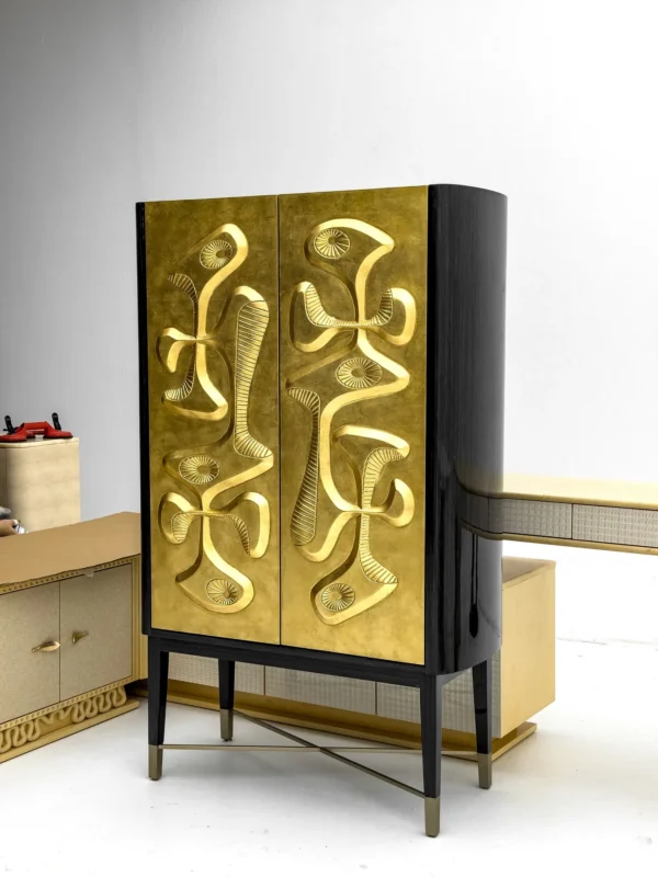 Gilded Relief Decorative Tall Cabinet on Brass Legs in brushed brass — in a room setting