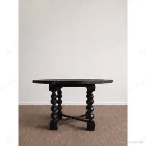 Courtyard Black Round Table on Hand-Carved Column Legs in black — in a room setting