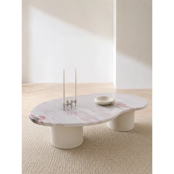 Pink Marble Organic Coffee Table on White Cylinder Legs in rose stone — in a room setting
