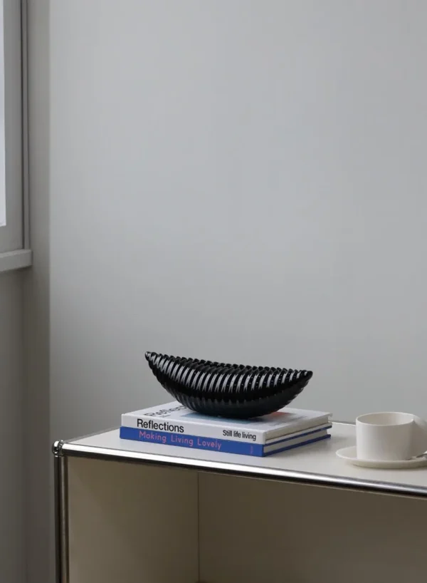 Glossy Black Ribbed Boat Bowl Ornament, Small in black — in a room setting