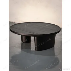 Round Black Wood Coffee Table on Sculpted Pedestal in black — in a room setting