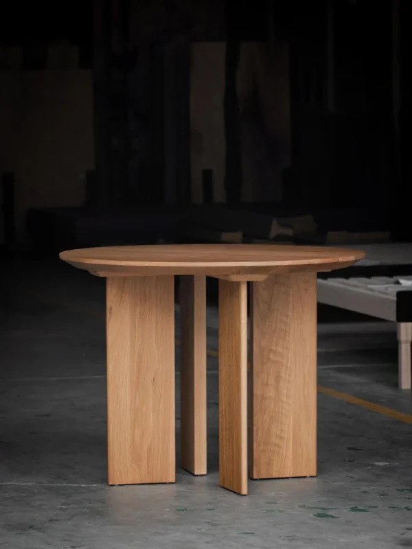 Solid Oak Round Table with Angled Panel Base in natural oak — in a room setting