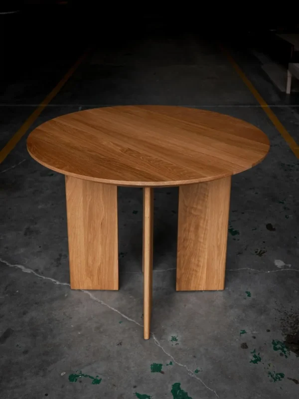 Solid Oak Round Table with Angled Panel Base in natural oak — in a room setting