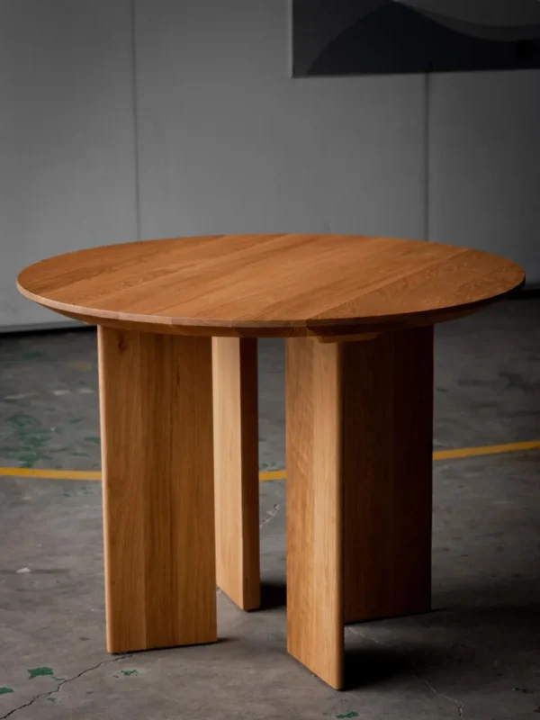 Solid Oak Round Table with Angled Panel Base in natural oak — in a room setting