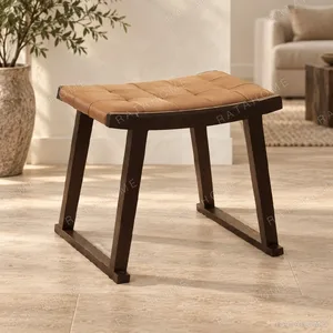Woven Tan Leather Saddle Stool on Dark Wood Sled in clay — in a room setting