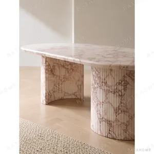 Pink Marble Oval Dining Table on Twin Stone Cylinders in rose stone — in a room setting