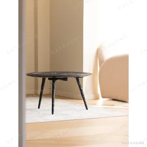 Hand-Carved Teak Round Coffee Table on Textured Metal Legs in clay — in a room setting