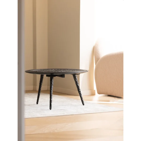 Hand-Carved Teak Round Coffee Table on Textured Metal Legs in clay — in a room setting