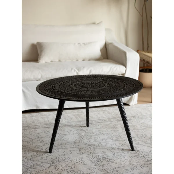 Hand-Carved Teak Round Coffee Table on Textured Metal Legs in clay — in a room setting