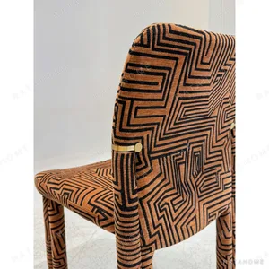 Geometric Pattern Upholstered Dining Chair with Brass Detail in rust — in a room setting