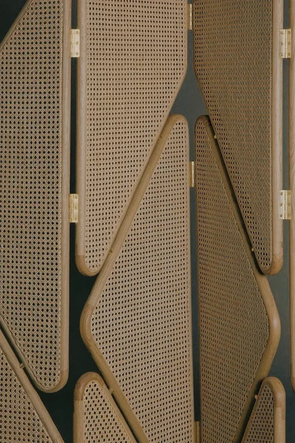 Geometric Cane Panel Folding Screen with Aged Hinges in natural oak — in a room setting
