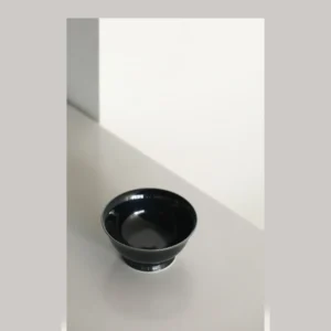 Hand-Made Black Gold Glaze Footed Tea Bowl in black — in a room setting