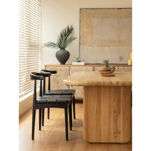 Horn-Back Teak Dining Chair with Woven Leather Seat in black — in a room setting