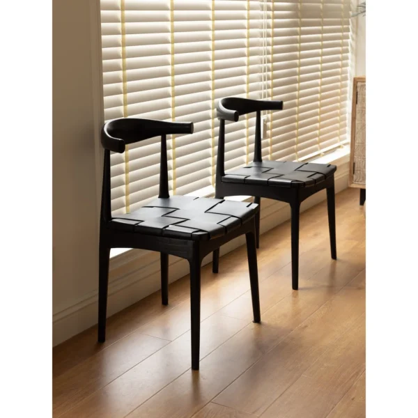 Horn-Back Teak Dining Chair with Woven Leather Seat in black — in a room setting