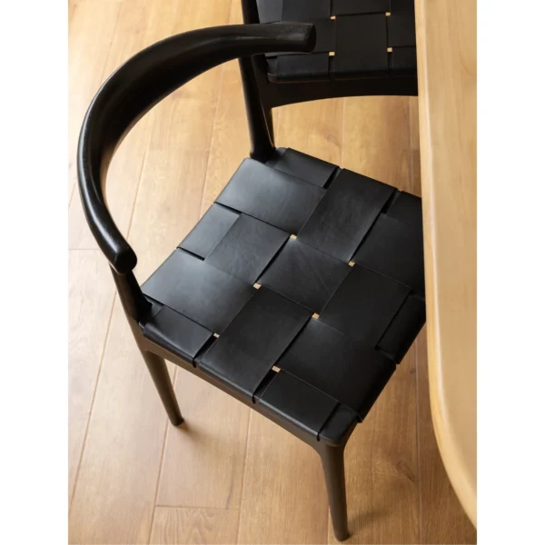 Horn-Back Teak Dining Chair with Woven Leather Seat in black — in a room setting