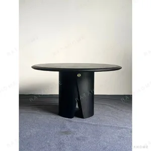 Black Round Dining Table on Sculpted Split Pedestal in black — in a room setting