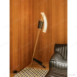 Kite Sculptural Floor Lamp with Perforated Curved Shade in brushed brass — in a room setting