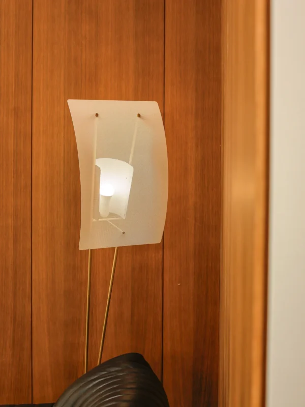 Kite Sculptural Floor Lamp with Perforated Curved Shade in brushed brass — in a room setting